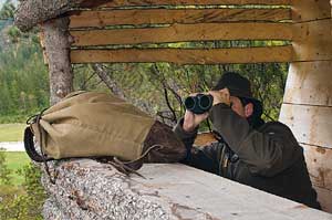 A man using Swarovski binoculars from a blind