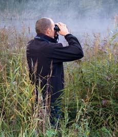 Man Using Binocular in a field with fog
